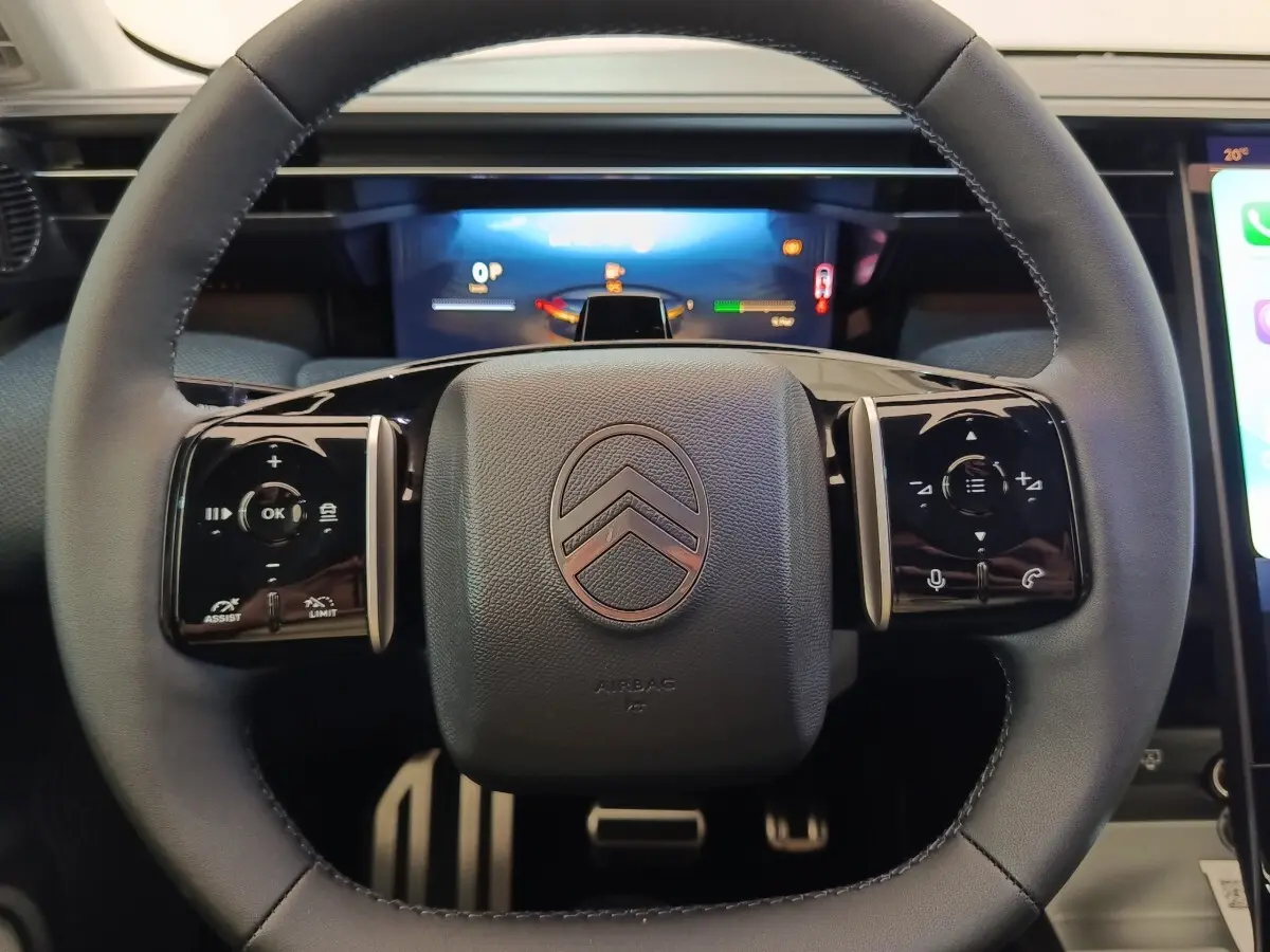 Vue rapprochée du volant cuir noir de la Citroën C5 Hybride 2026 avec commandes multifonctions et logo central.