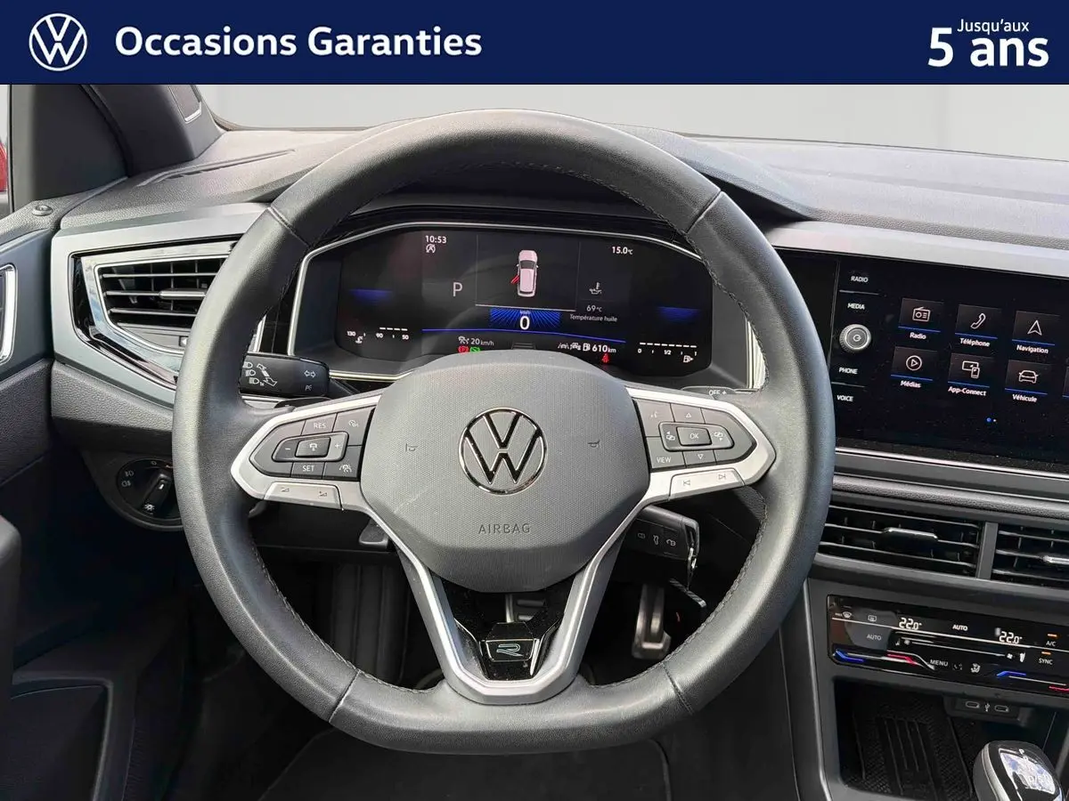 Vue intérieure centrée sur le volant cuir multifonctions et le tableau de bord digital de la Volkswagen Polo rouge 2025.