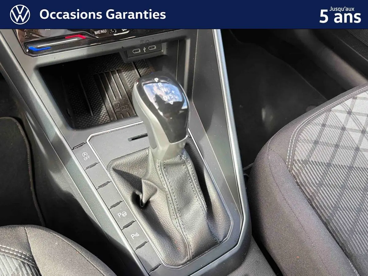 Levier de vitesse DSG7 en gros plan avec console centrale et siège avant droit tissu gris à motifs.