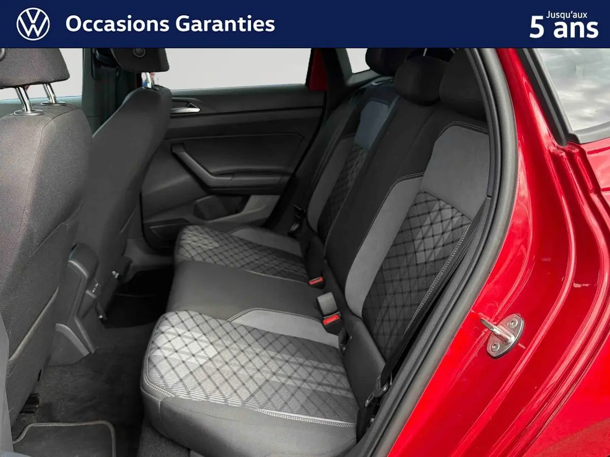Vue intérieure côté arrière droit de la Volkswagen Polo rouge 2025, montrant la banquette arrière en tissu gris et noir.