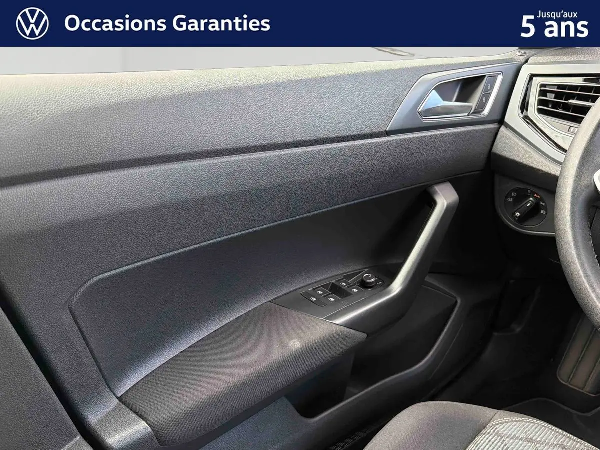Vue rapprochée de la porte avant gauche intérieure de la Volkswagen Polo 2025 avec commandes électriques et poignée angulaire.