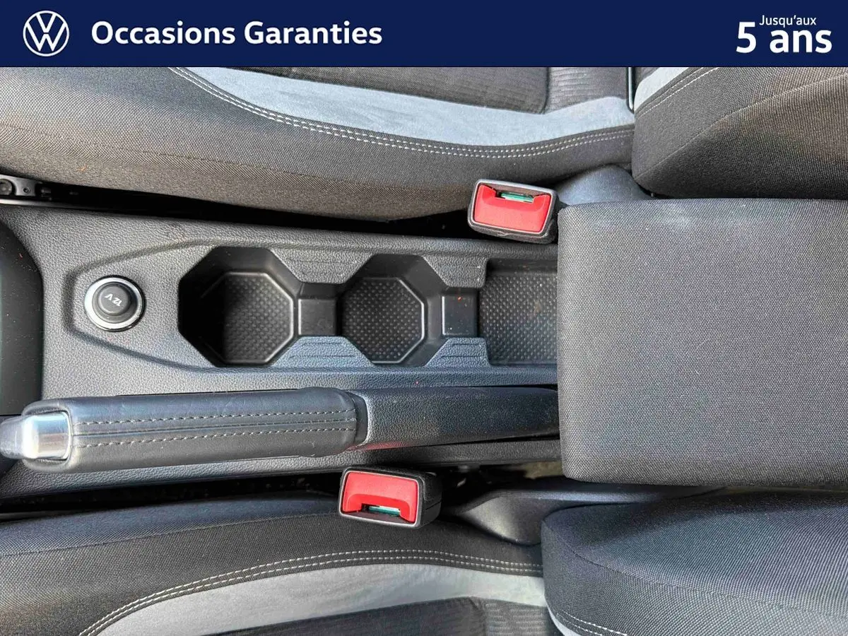 Vue rapprochée de la console centrale noire avec frein à main et deux ceintures rouges dans l’habitacle d’une Volkswagen Polo.