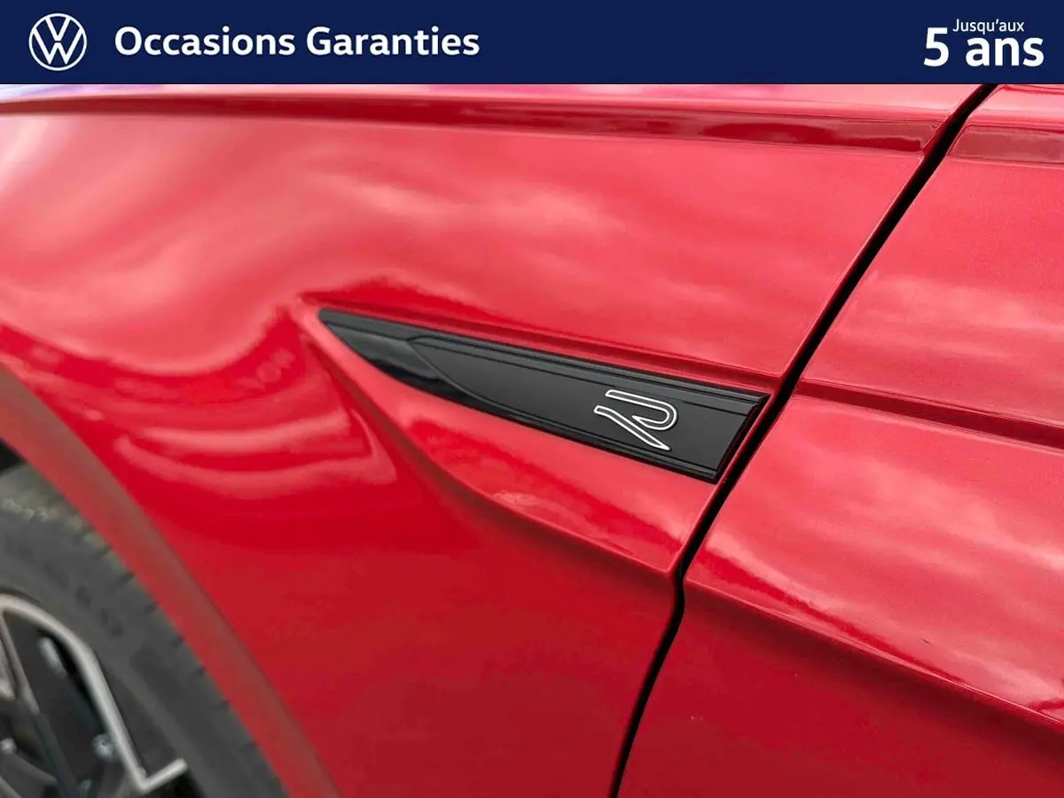 Détail de l'aile avant gauche rouge métallisée de la Volkswagen Polo 2025 avec logo R noir et jante alliage visible.