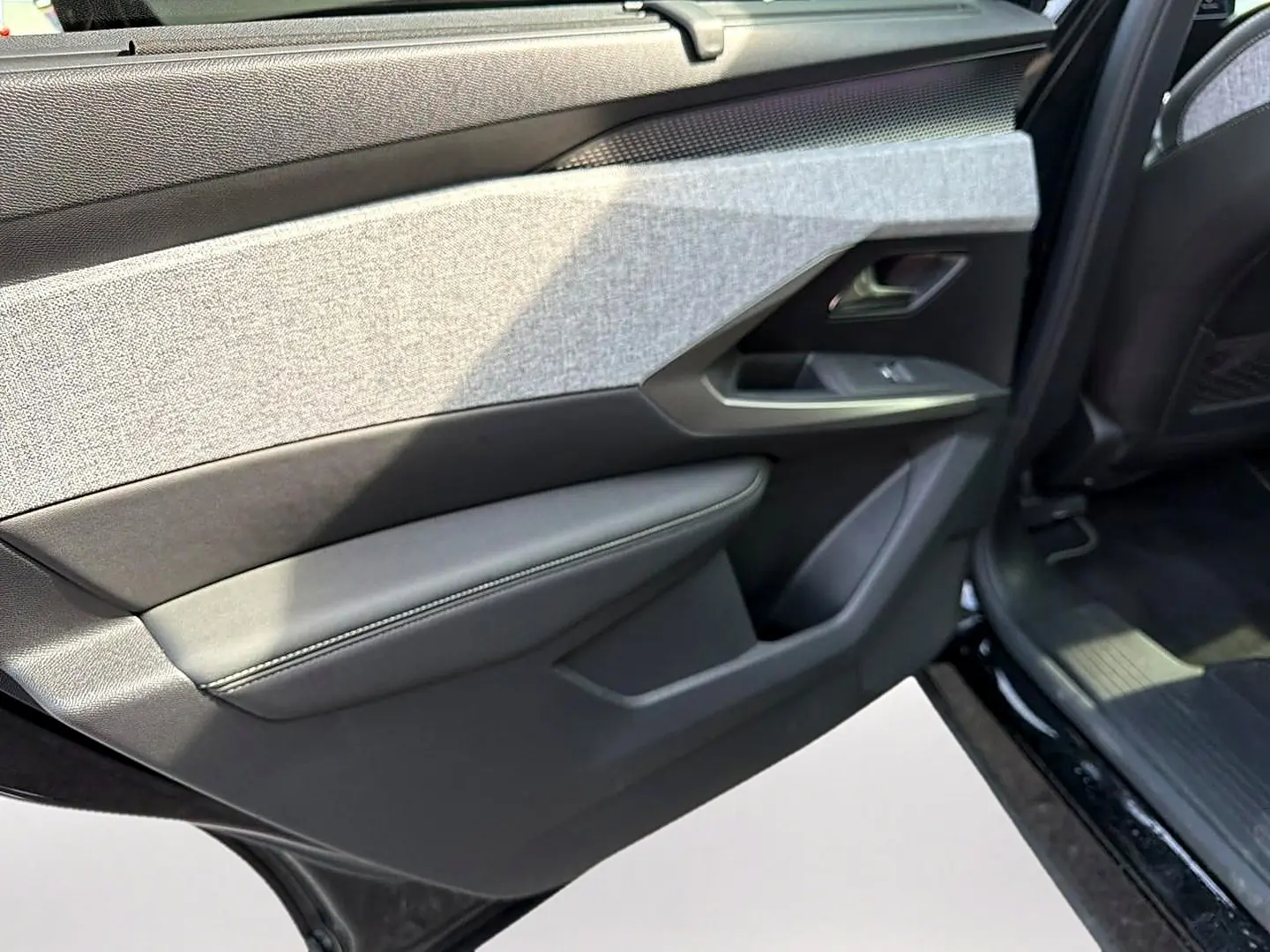 Vue rapprochée de la porte arrière droite noire du Peugeot 5008 Hybrid 145 GT, avec garniture tissu et cuir gris.