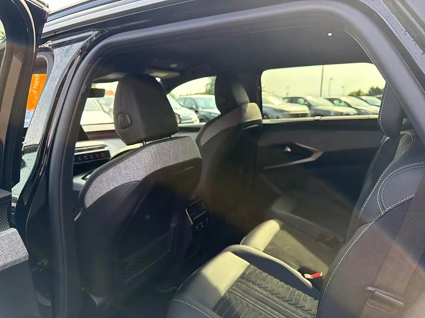 Vue intérieure côté droit du Peugeot 5008 Hybrid 145 GT 2025 noir, montrant les sièges arrière et détails de la porte ouverte.
