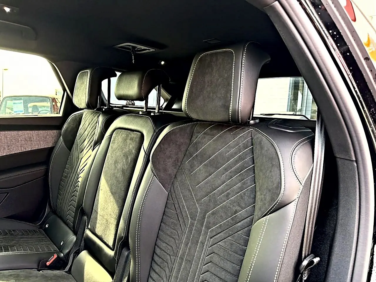 Vue intérieure côté droit montrant les sièges arrière en cuir noir avec surpiqûres contrastantes du Peugeot 5008 Hybrid 145 GT.