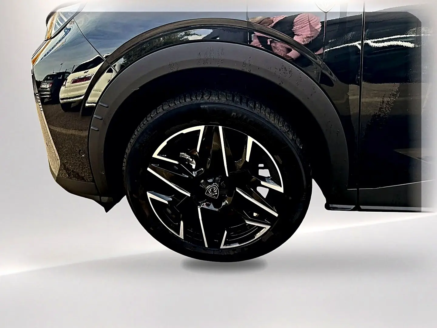 Gros plan sur la roue avant gauche noire du Peugeot 5008 Hybrid 145 GT e-dcs6 noir avec jante alu stylisée.