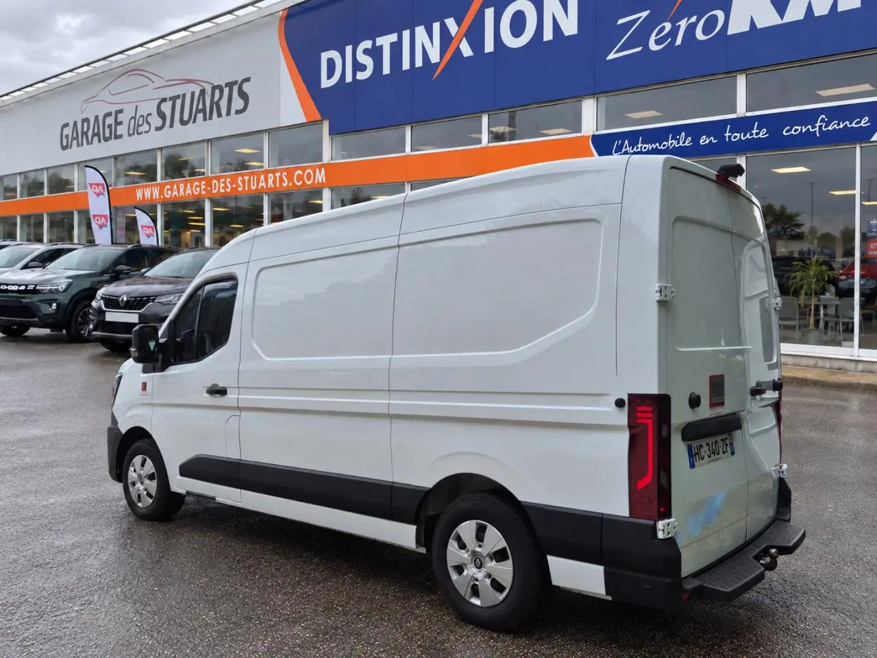 Renault Master blanc vu en 3/4 arrière droit, fourgon L2H2 avec feux arrière LED distinctifs, stationné devant un garage.