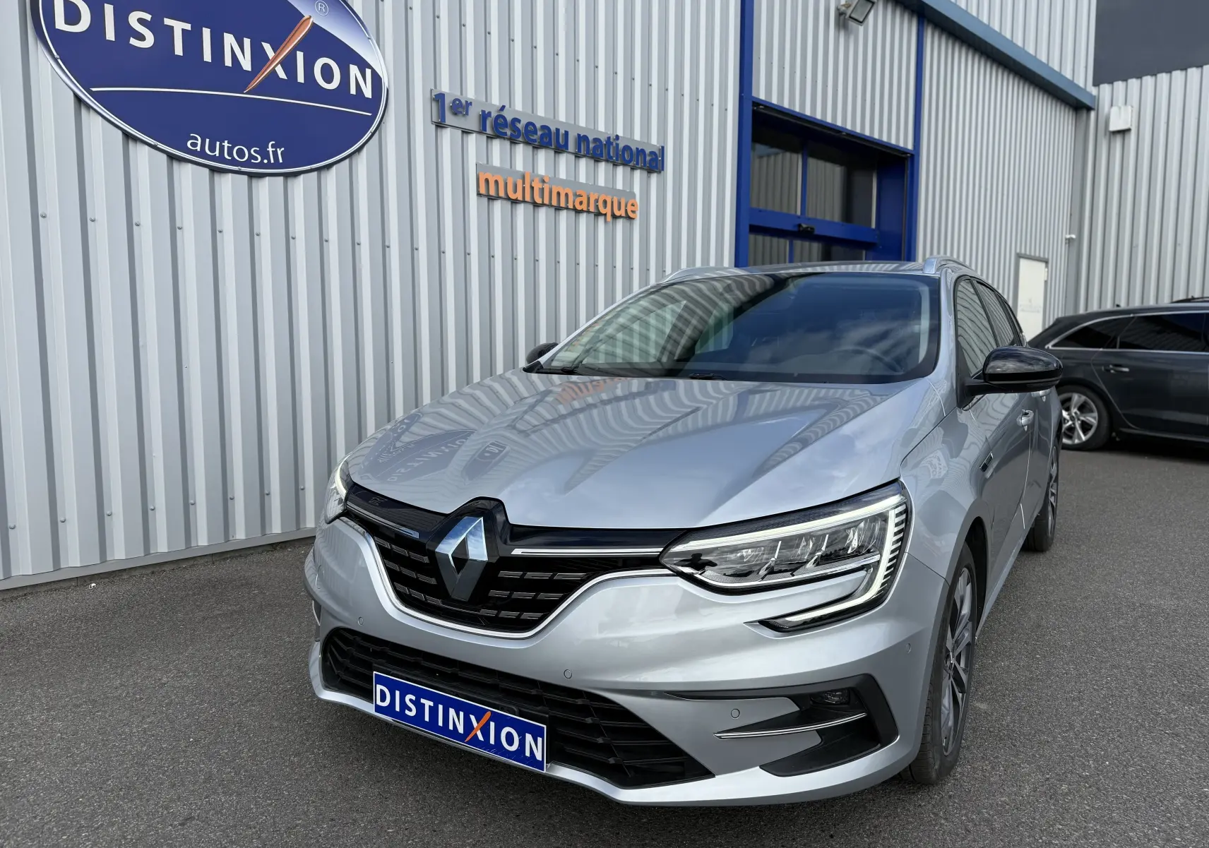Renault Mégane Break gris Highland Metal vue 3/4 avant droit, avec calandre noire et phares LED distinctifs.