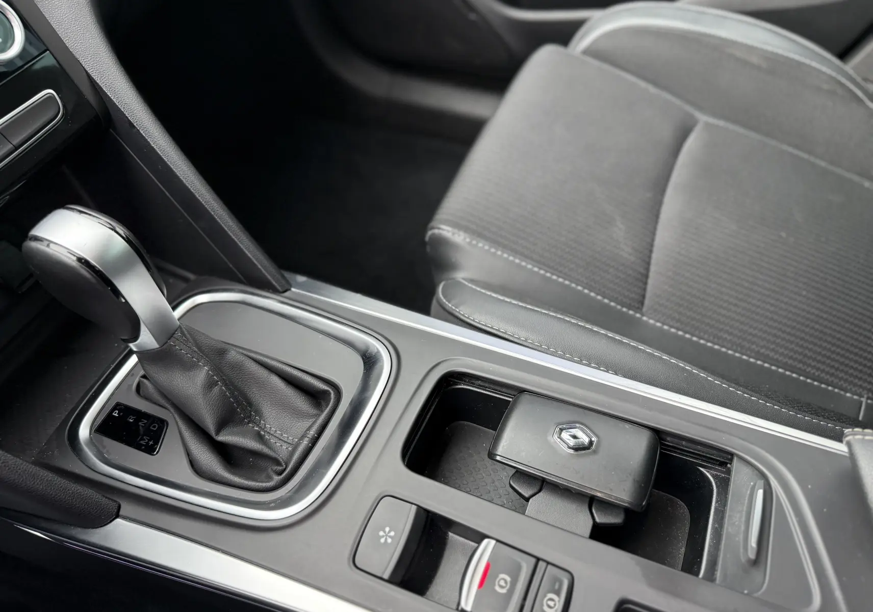 Gros plan sur la console centrale de la Renault Mégane Break 2024 avec levier de boîte auto et clé grise Highland Metal.