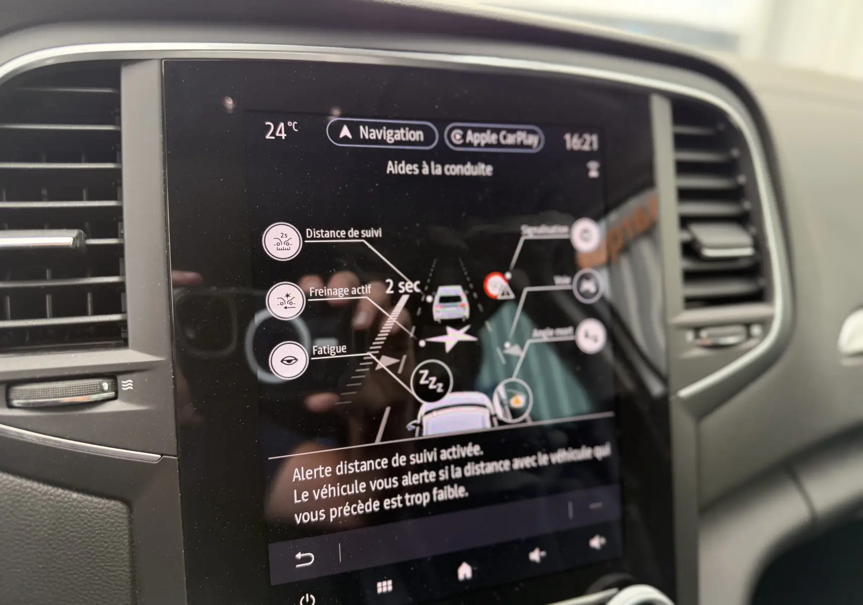 Écran tactile du système d’aide à la conduite de la Renault Mégane Break 2024 affichant alertes et réglages à 24°C.