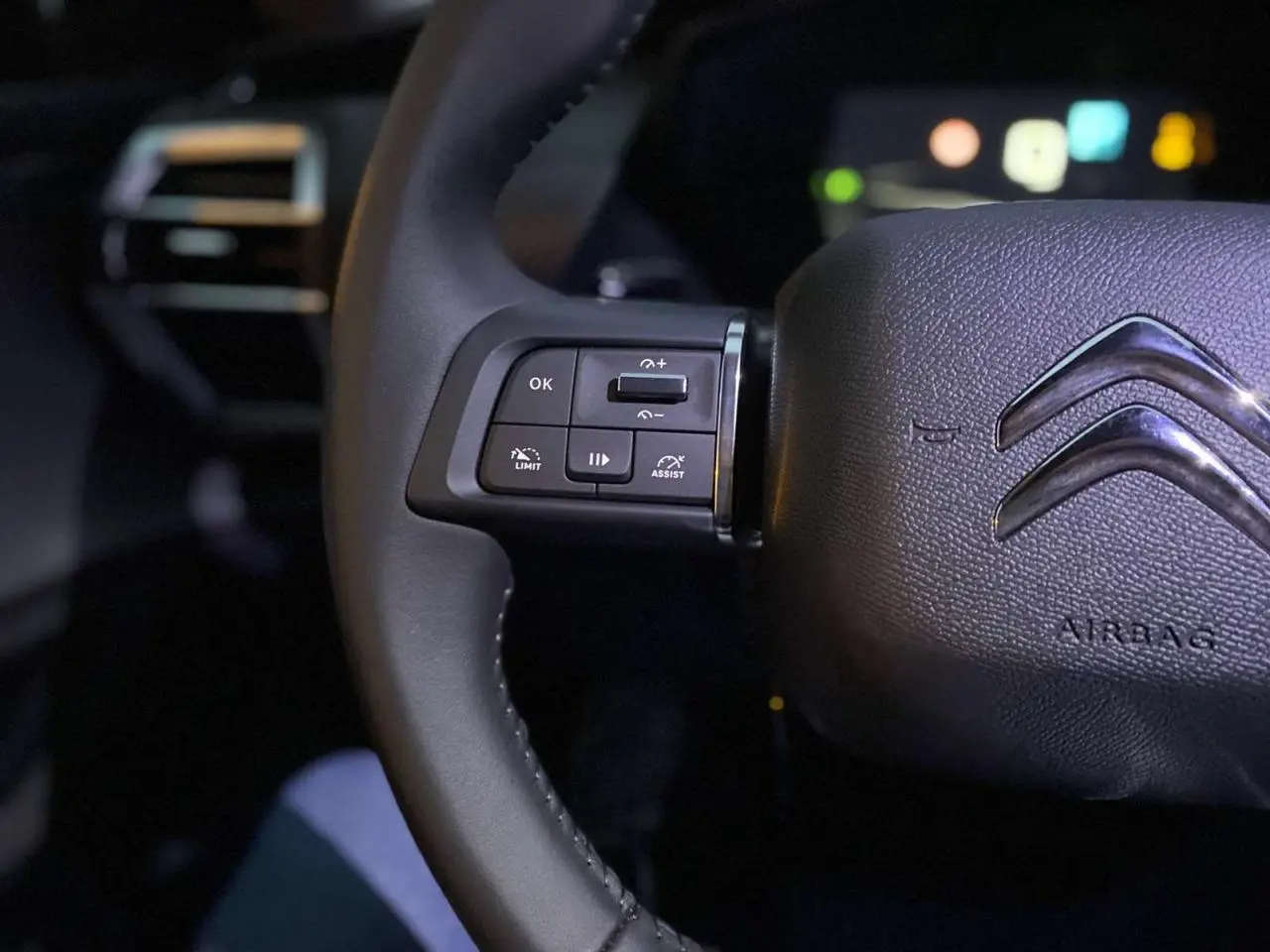 Gros plan sur le volant cuir noir du Citroën C5 X 2023 avec commandes intégrées côté gauche et logo chromé central.