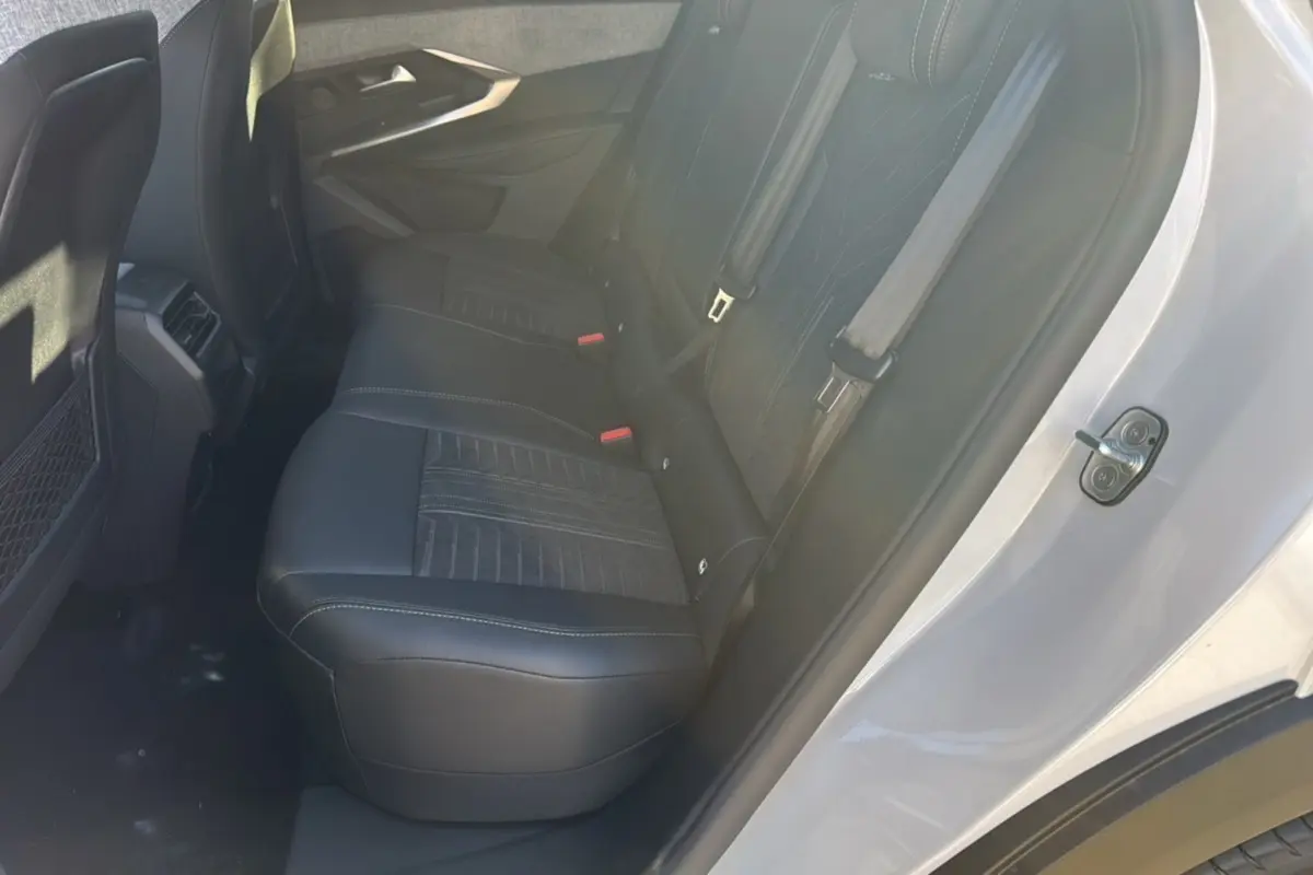 Vue côté droit de l'habitacle arrière du Peugeot 3008 Hybrid 136 GT Plus blanc okénite avec sièges noirs en cuir et tissu.