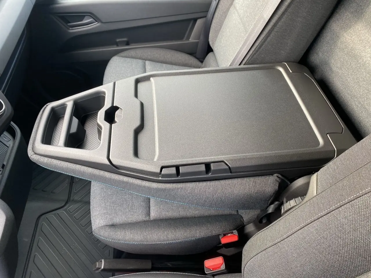 Vue intérieure rapprochée du siège passager gris avec accoudoir central et tablette rabattable du Renault Master 2025.