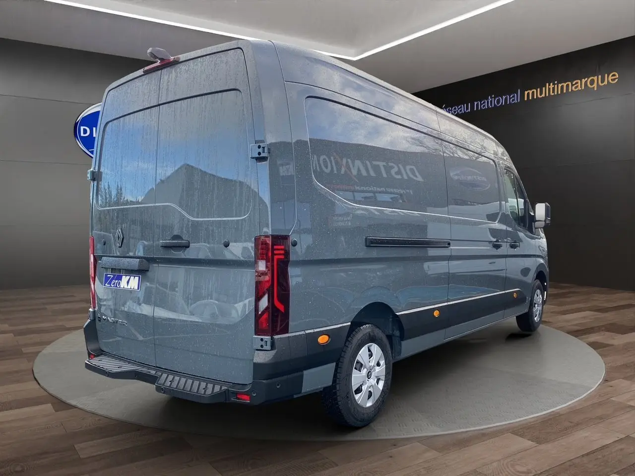 Vue 3/4 arrière droit du Renault Master gris urbain 2025 avec hayon et feux arrière verticaux allumés.
