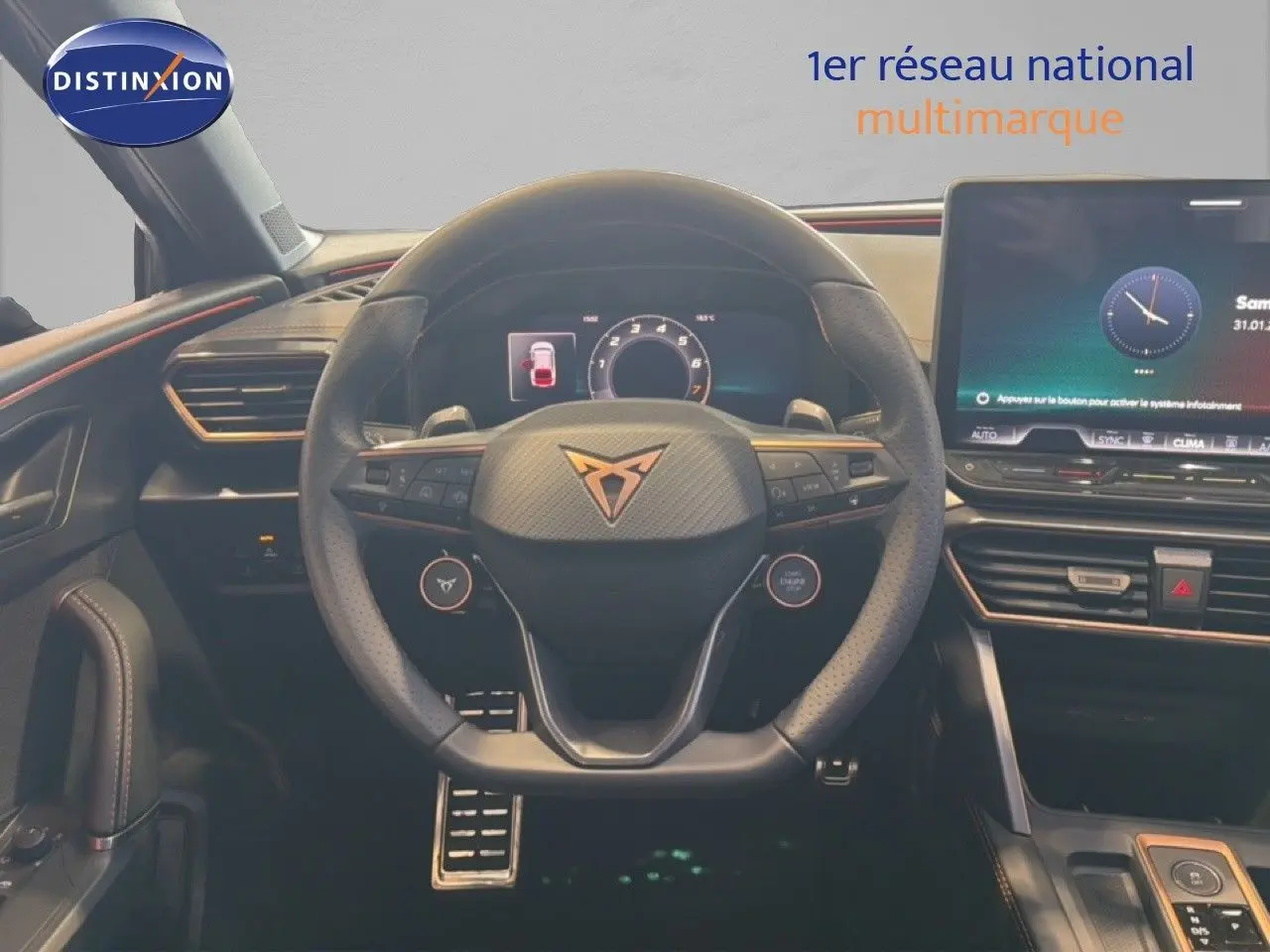 Vue intérieure centrée sur le volant CUPRA avec tableau de bord numérique et écran tactile, ambiance noire et orange.