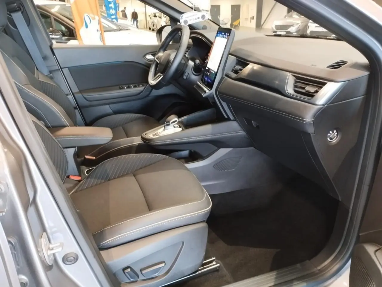 Vue intérieure côté conducteur du Renault SYMBIOZ gris Cassiopée, avec sièges noirs et écran tactile vertical.