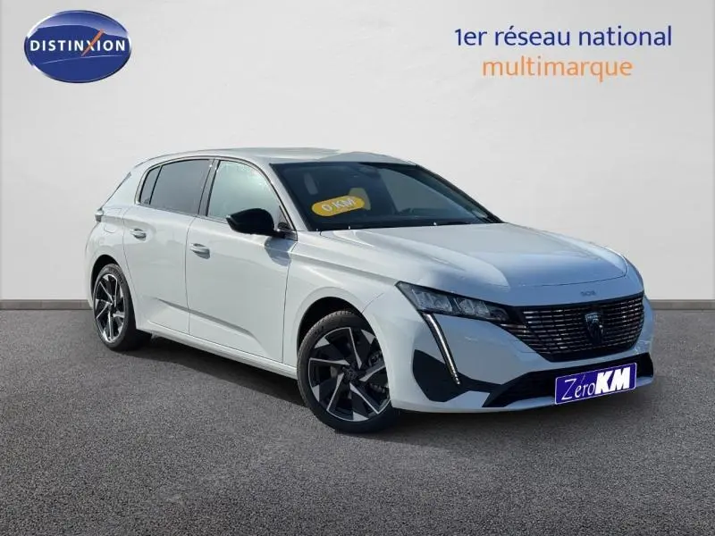 Peugeot 308 blanc Okénite vue 3/4 avant droit, avec calandre noire et jantes alliage distinctives.