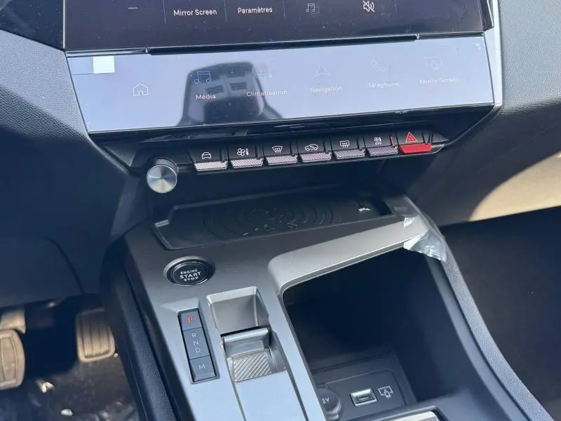 Gros plan sur la console centrale de la Peugeot 308 blanche, avec écran tactile, boutons de commande et levier de boîte auto.