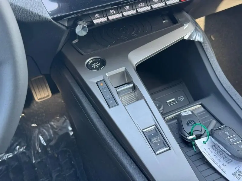 Vue rapprochée de la console centrale grise de la Peugeot 308 2025 avec boîte auto et boutons de démarrage et mode de conduite.
