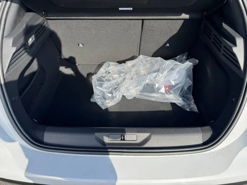 Vue plongeante sur le coffre ouvert d'une Peugeot 308 blanc Okénite, avec un sac plastique transparent à l'intérieur.