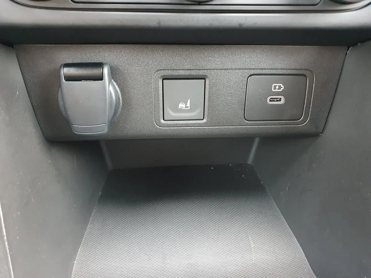 Détail du tableau de bord avec prise USB-C et bouton rabattement banquette du Dacia Jogger vert cèdre.