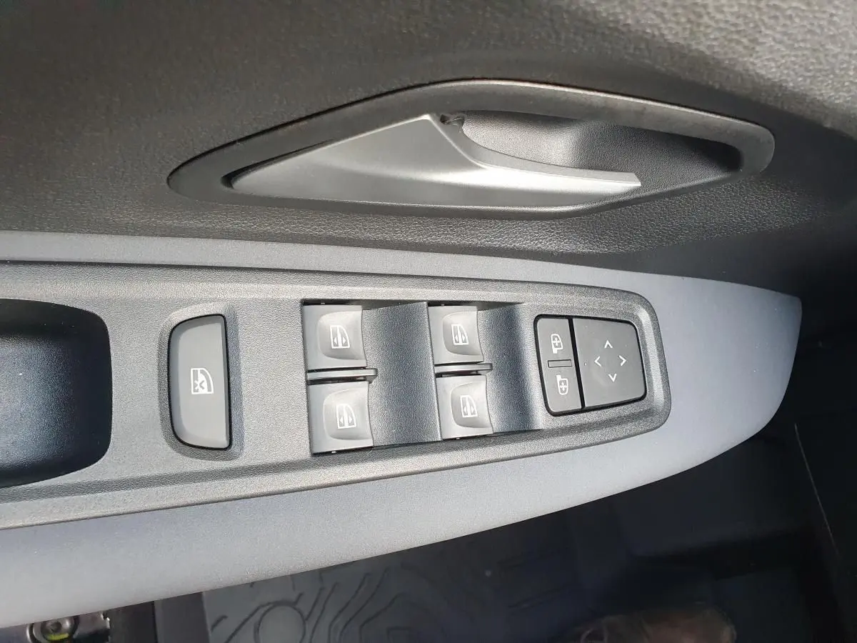 Vue rapprochée des commandes des vitres et rétroviseurs sur la porte côté conducteur d’un Dacia Jogger vert cèdre.