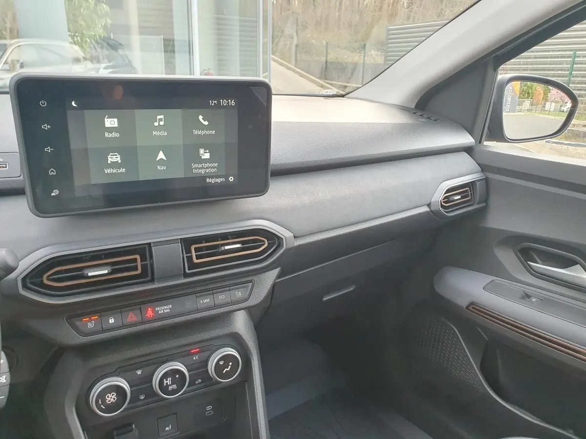 Vue intérieure côté passager du tableau de bord et écran tactile du Dacia Jogger 1.6 Hybrid 2026 avec finitions noires et détails cuivre.