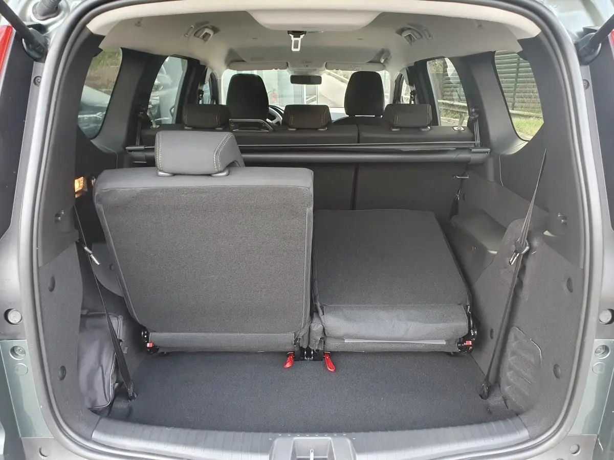 Vue arrière du coffre du Dacia Jogger vert cèdre 2026, banquette arrière partiellement rabattue côté droit.