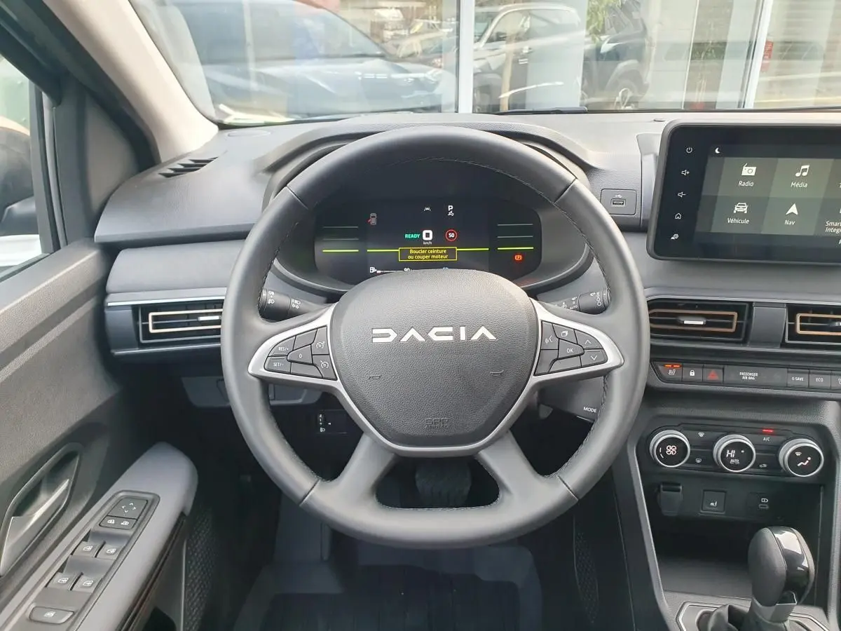Vue intérieure centrée sur le volant DACIA du Jogger 2026 avec tableau de bord numérique et écran tactile.