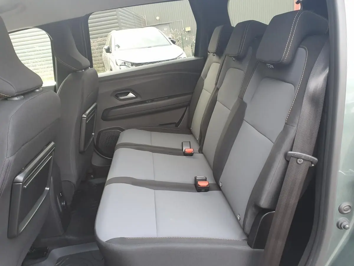Vue latérale droite de la banquette arrière grise et noire du Dacia Jogger 2026 vert cèdre, avec ceinture de sécurité visible.
