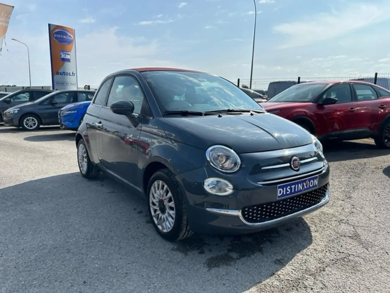 Fiat 500C gris avec toit rouge vue 3/4 avant droit, capote fermée, sur parking en extérieur.