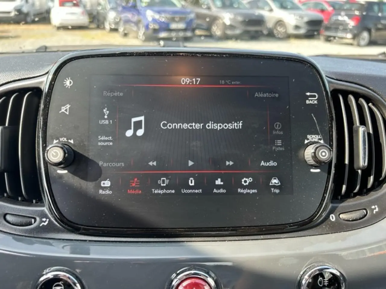 Écran tactile central du tableau de bord de la Fiat 500C gris/rouge, affichant le menu audio et connectivité.