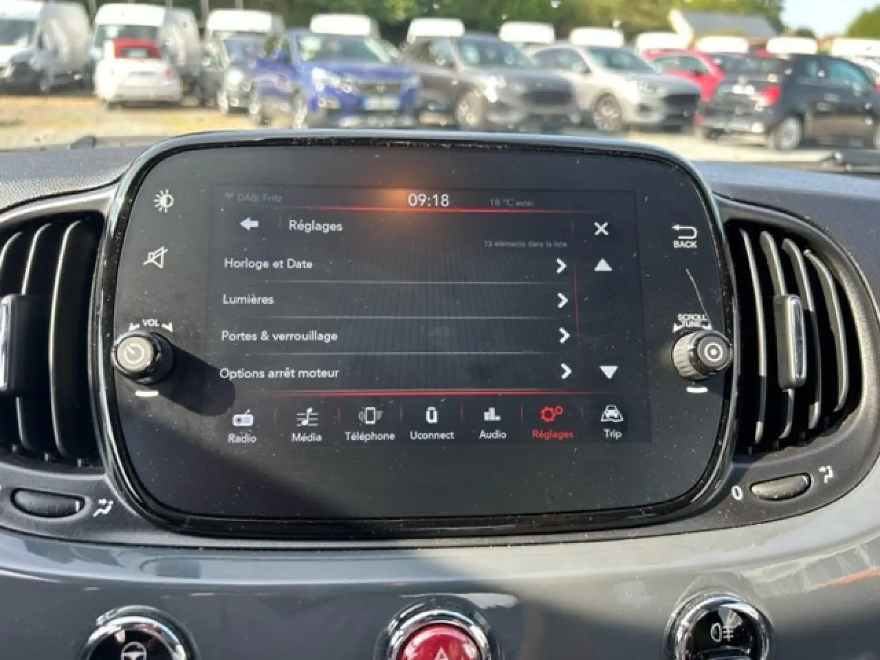 Vue rapprochée de l'écran tactile central du tableau de bord gris du Fiat 500C cabriolet, avec commandes visibles.