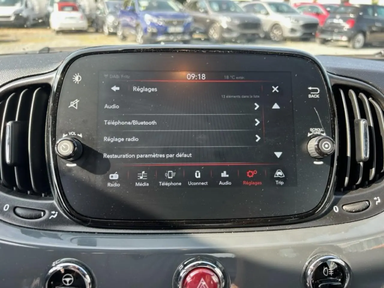 Écran tactile central du tableau de bord de la Fiat 500C gris/rouge, affichant le menu Réglages en plein jour.