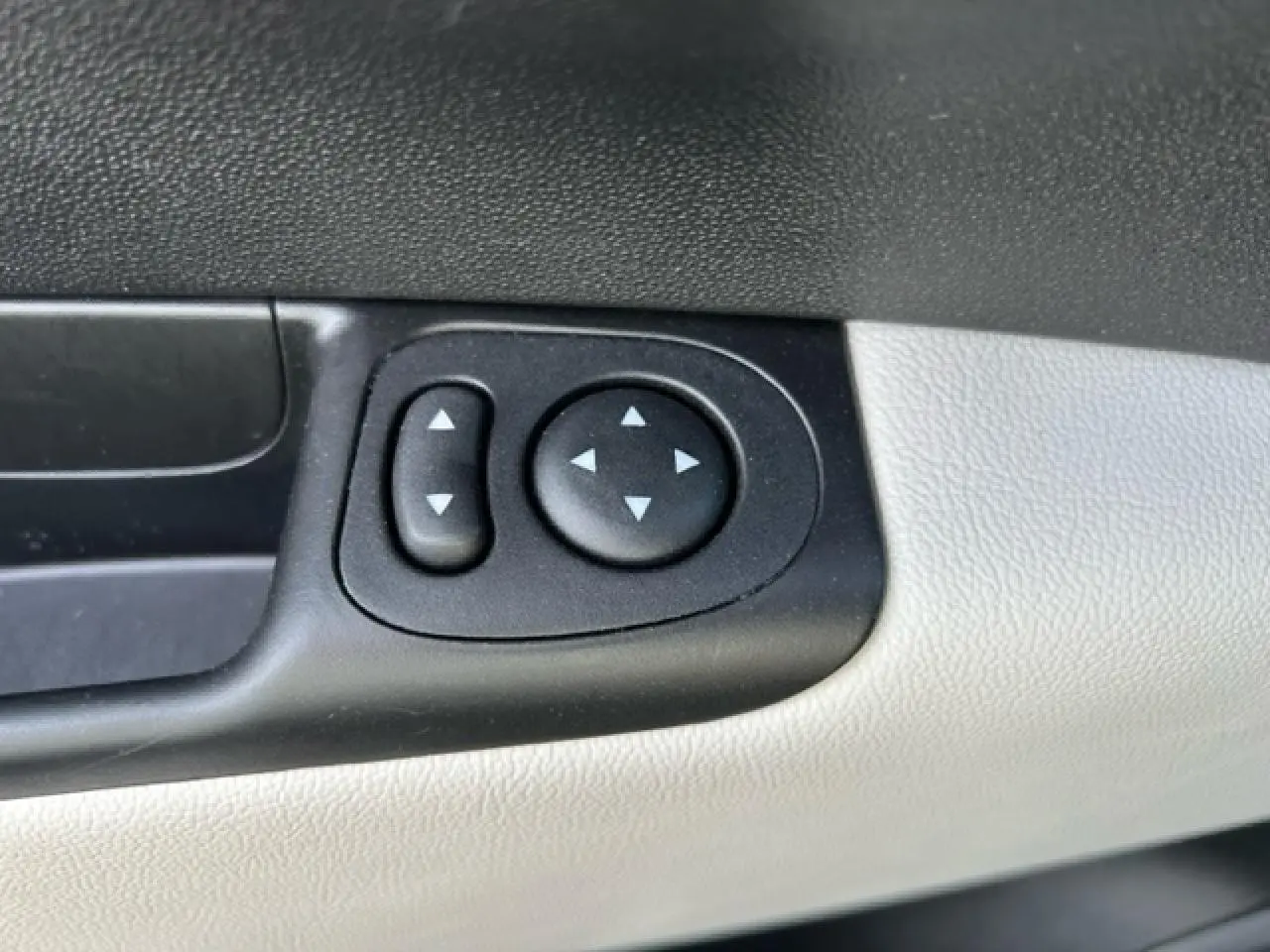 Boutons de réglage des rétroviseurs électriques sur la portière côté gauche d'une Fiat 500C gris et rouge.