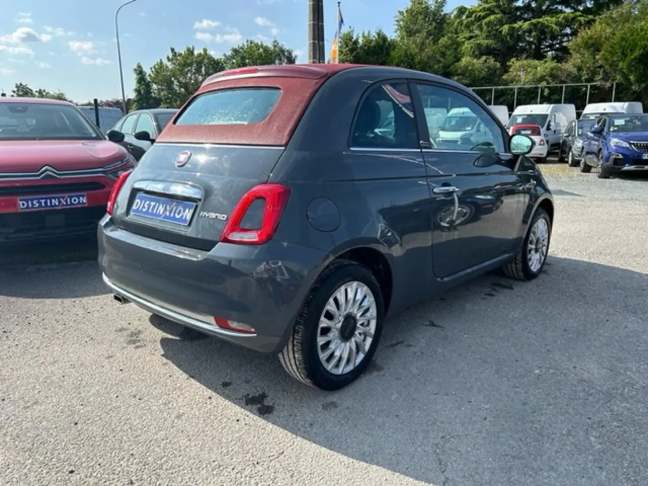 Fiat 500C gris avec capote rouge vue 3/4 arrière droit, soulignant son toit cabriolet fermé et ses jantes distinctives.