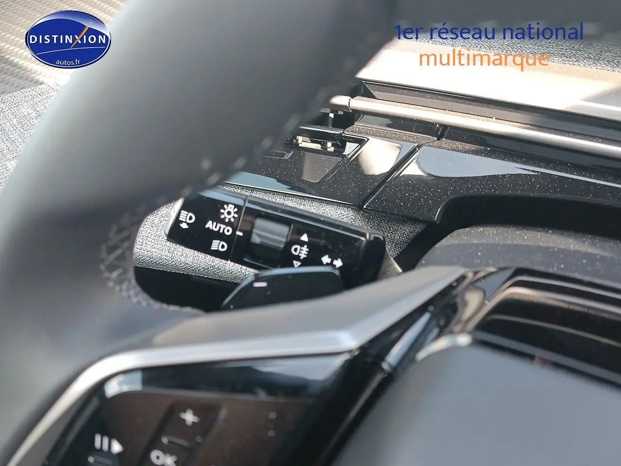 Détail du commodo d’éclairage et partie du volant cuir noir du Peugeot 3008 1.2 hybrid 145 allure, intérieur moderne.