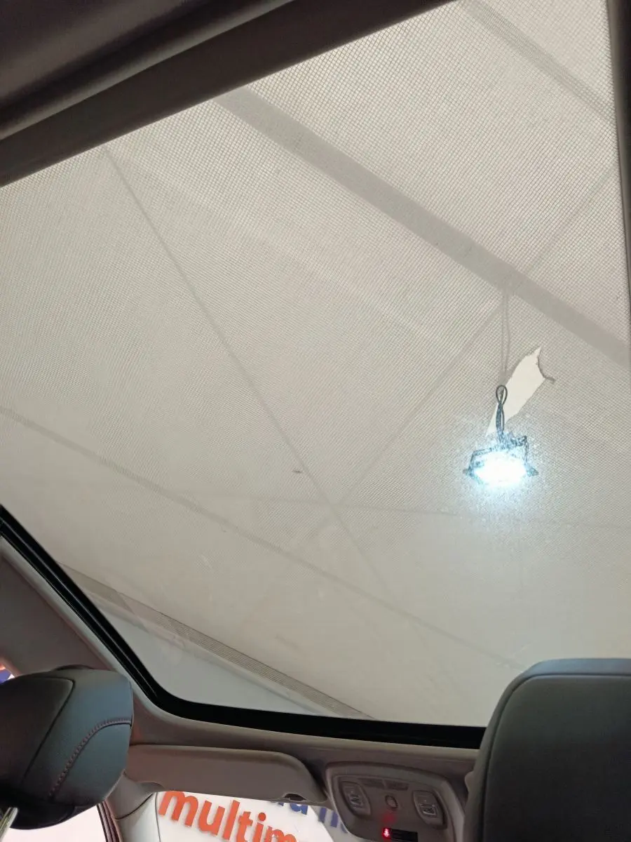 Vue intérieure du toit panoramique du Renault Kadjar blanc, avec éclairage et partie des sièges avant visibles.