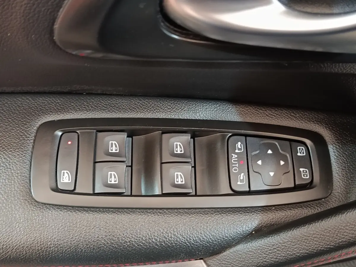 Vue rapprochée des commandes de lève-vitres et rétroviseurs sur la porte côté conducteur du Renault Kadjar blanc.