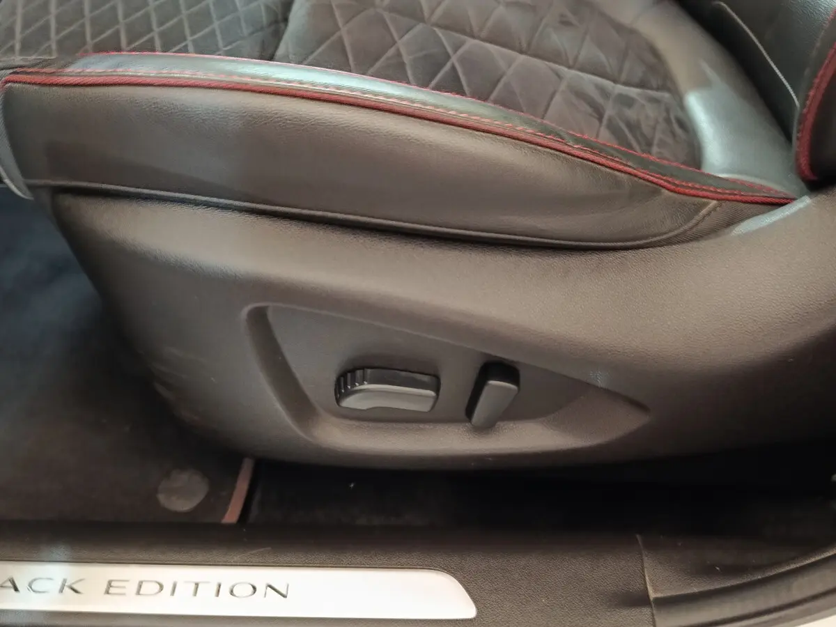 Gros plan sur la commande de réglage du siège cuir noir avec surpiqûres rouges du Renault Kadjar Black Edition.