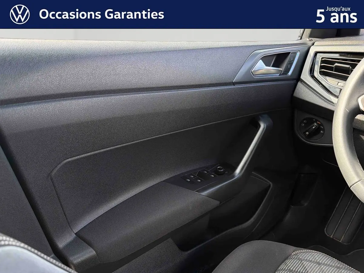Intérieur côté conducteur du Volkswagen Taigo 2025, montrant la portière noire avec commandes des vitres et partie du volant cuir.