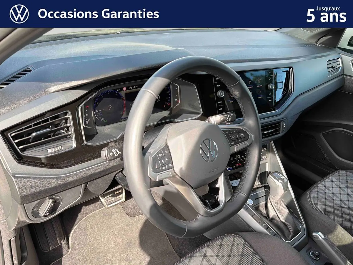 Vue intérieure du poste de conduite du Volkswagen Taigo gris, avec volant cuir multifonctions et écran tactile central.