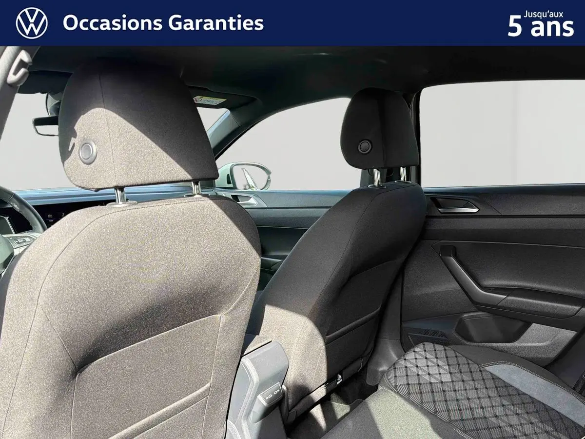 Vue intérieure arrière du Volkswagen Taigo 2025 montrant les sièges avant et la banquette arrière en tissu gris foncé.