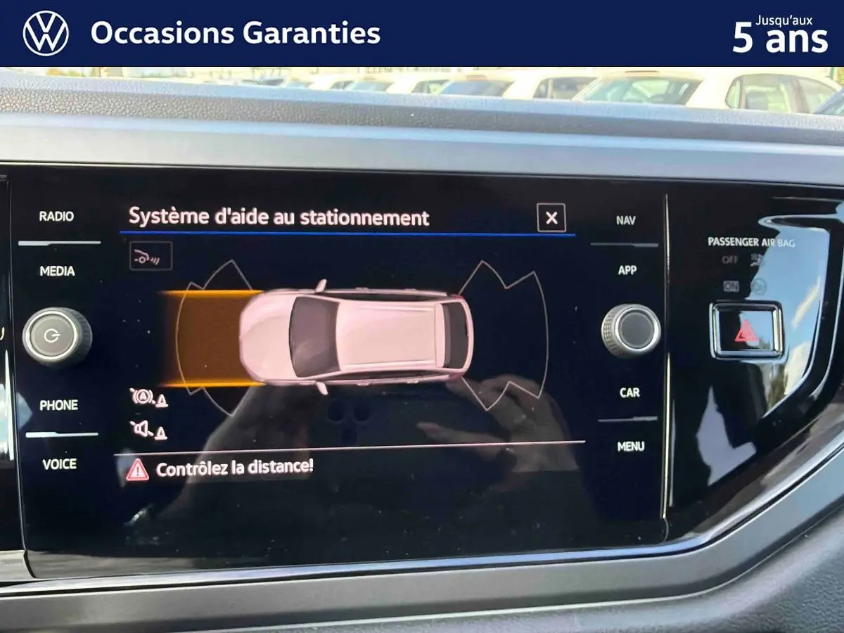 Écran tactile intérieur affichant le système d'aide au stationnement avec vue de dessus du véhicule gris.