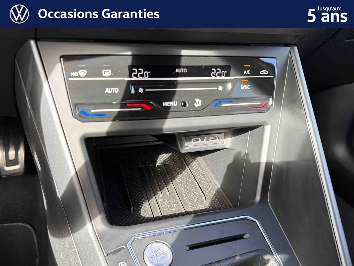 Vue rapprochée de la console centrale du Volkswagen Taigo gris, montrant les commandes de climatisation et le bouton start/stop.