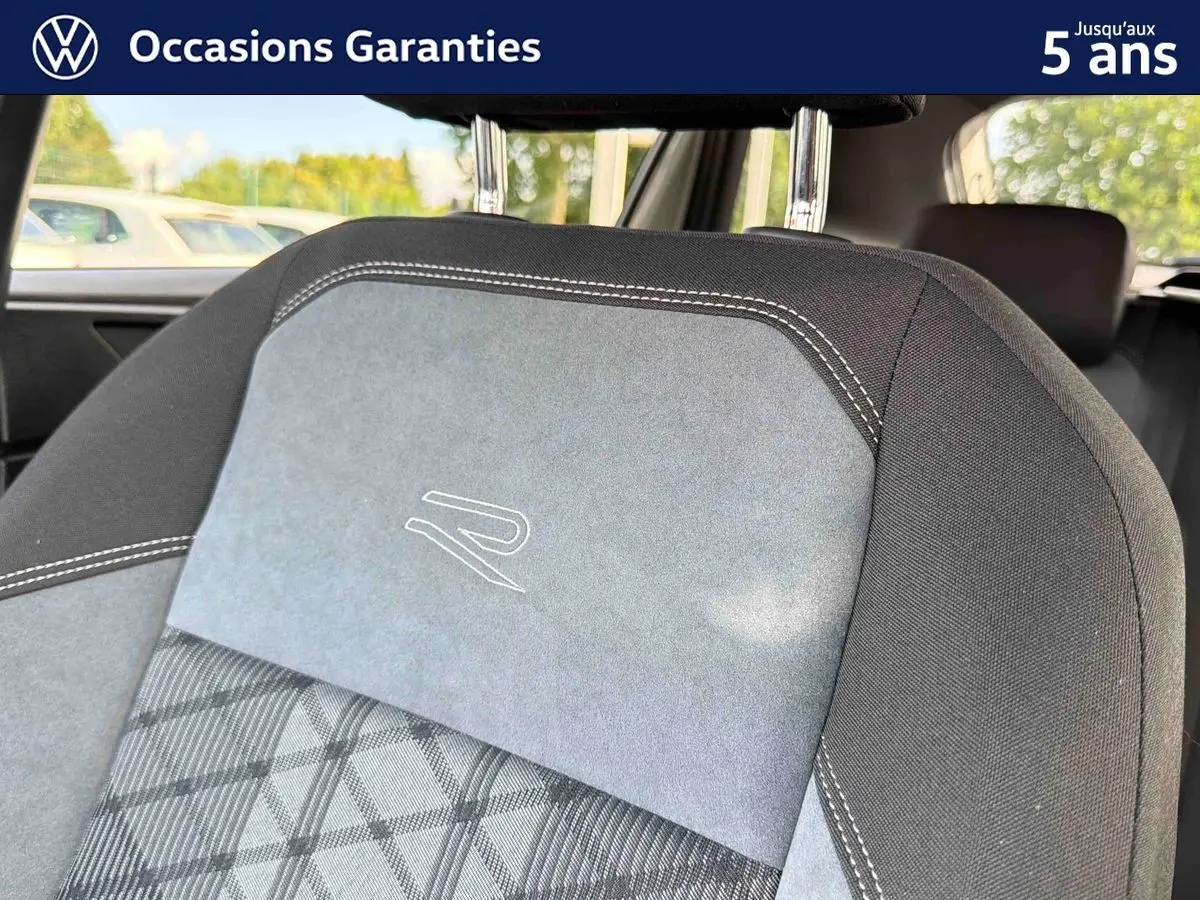 Détail de l’appui-tête avant gris et noir avec surpiqûres blanches et logo "R" brodé sur la Volkswagen Taigo.