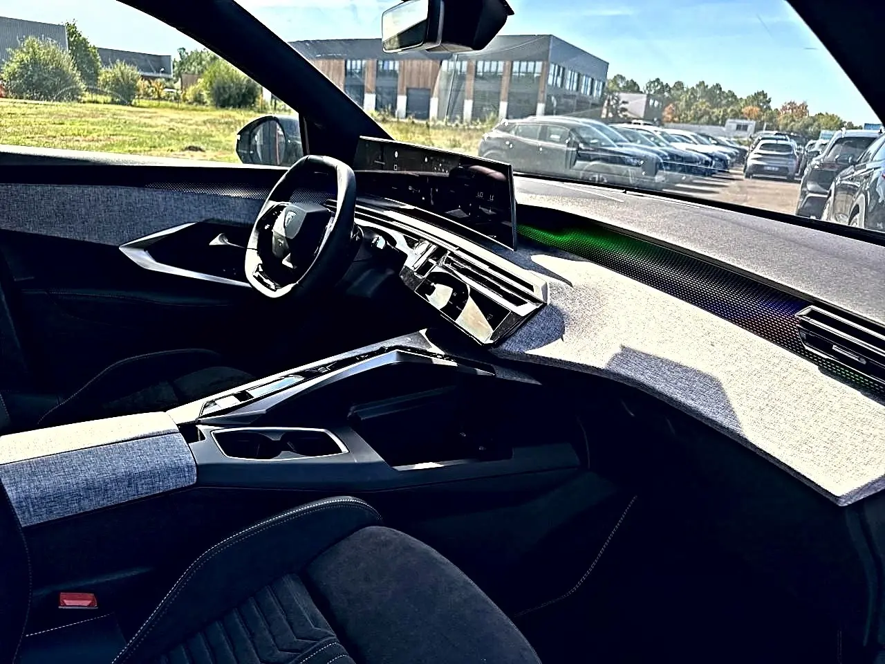 Vue intérieure côté conducteur du Peugeot 5008 Hybrid 145 GT 2025, tableau de bord clair avec écran tactile et volant multifonction.