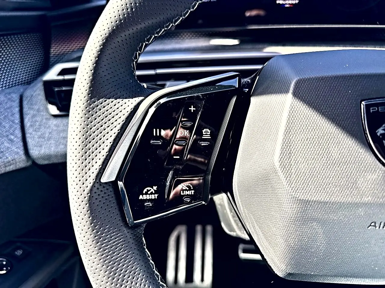 Gros plan sur le volant cuir perforé côté gauche du Peugeot 5008 Hybrid 145 GT 2025 avec commandes multifonctions.