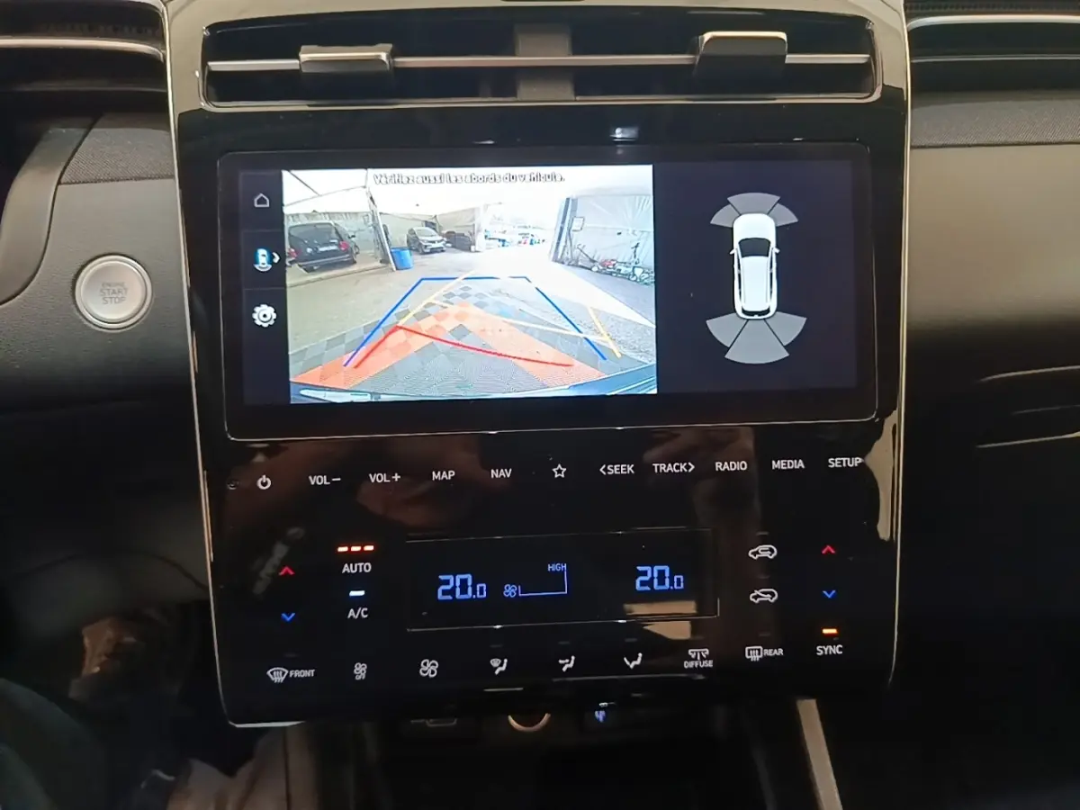Vue rapprochée de l’écran tactile central du Hyundai Tucson bleu, affichant la caméra de recul et la climatisation digitale.
